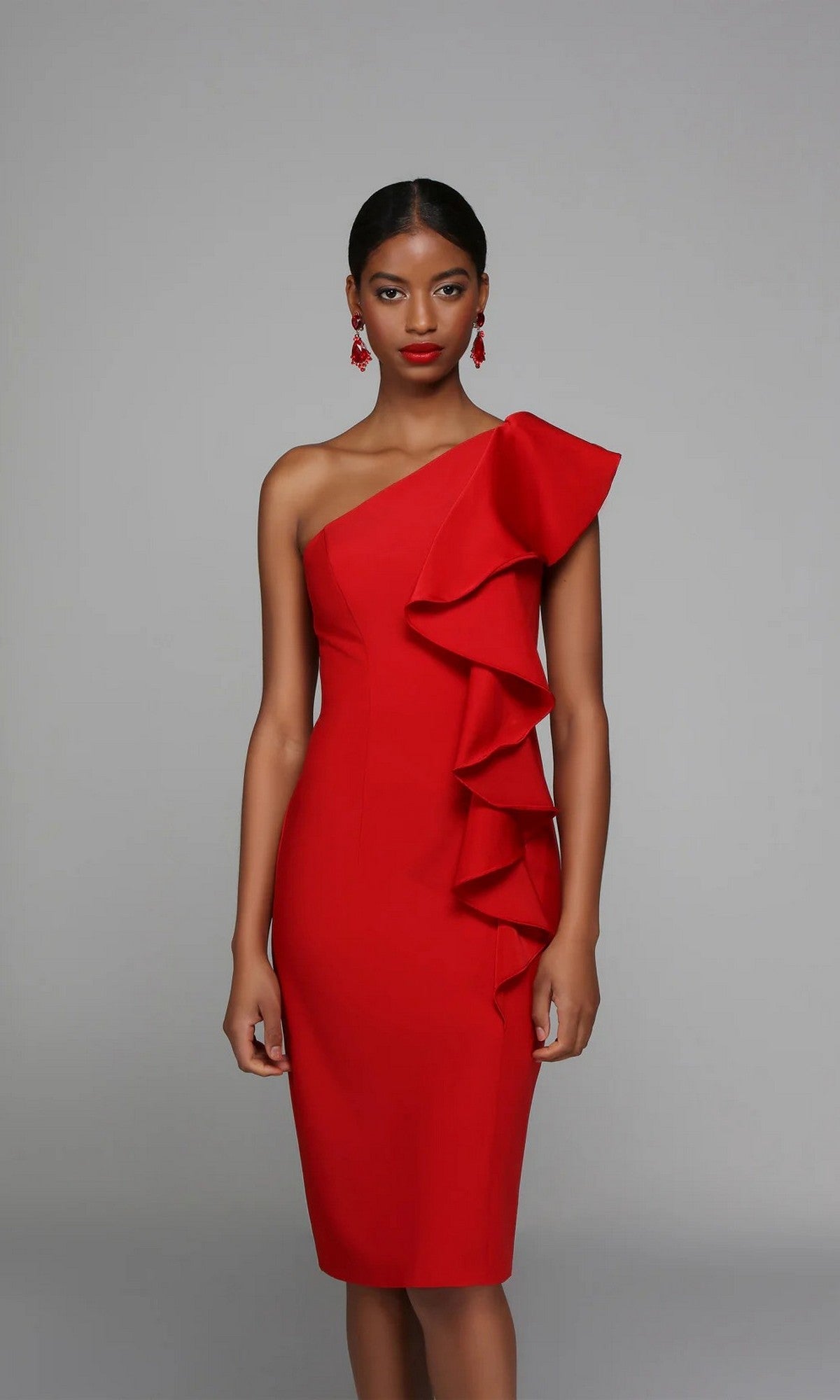 A woman models the Alyce 70008, a fitted semi-formal knee-length dress in vibrant red with one-shoulder design and layered ruffles on the right, set against a plain gray background.